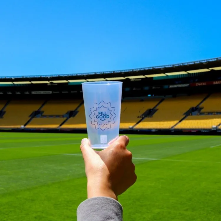 Custom FillGood Tumbler held in hands with Sky Stadium in the background