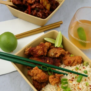 Reusable beige Betterdish with fried chicken and rice, served with lime and drink.