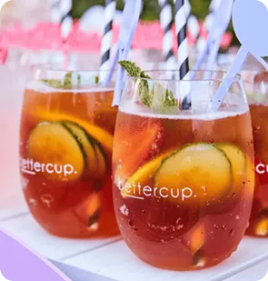 Close up photo of stemless bettercups filled with iced tea, cucumber slices, and striped straws.