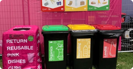 Pink branded reusable return bins beside organics, recycling, and landfill bins at Moomba Festival 2026